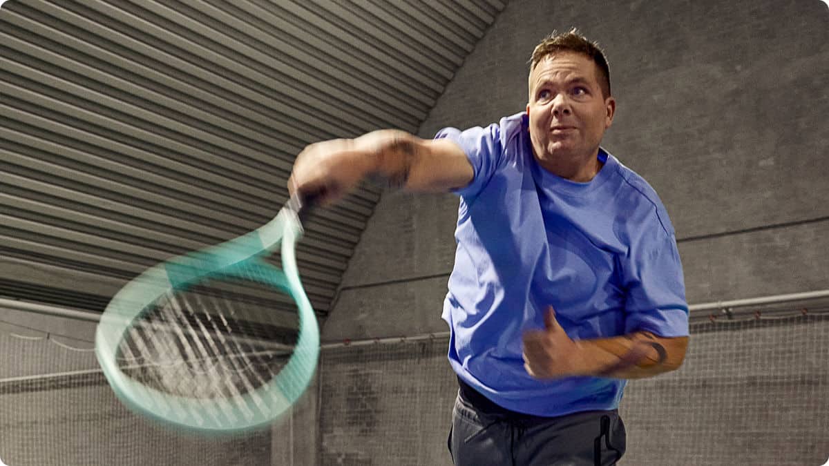 Un homme en t-shirt bleu joue au tennis