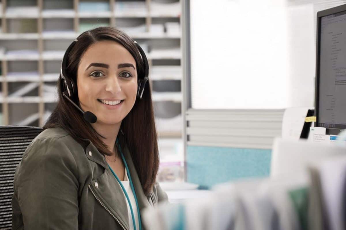 Frau mit Headset lacht in Kamera