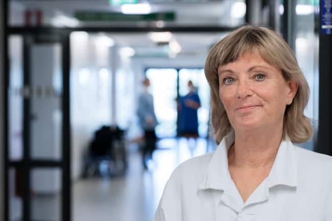 Medizinische Fachperson mit blonden Haaren in einem Klinik-Flur